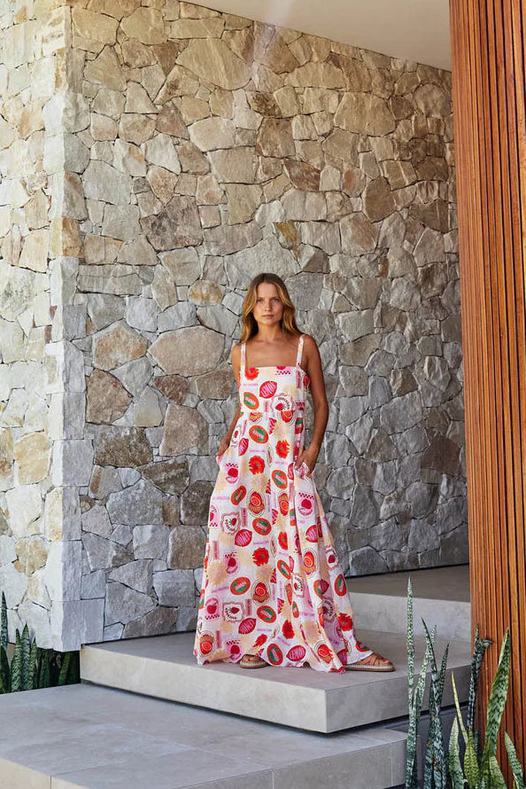 Woman in a floral dress standing on stone steps outside a modern building with stone and wooden walls.