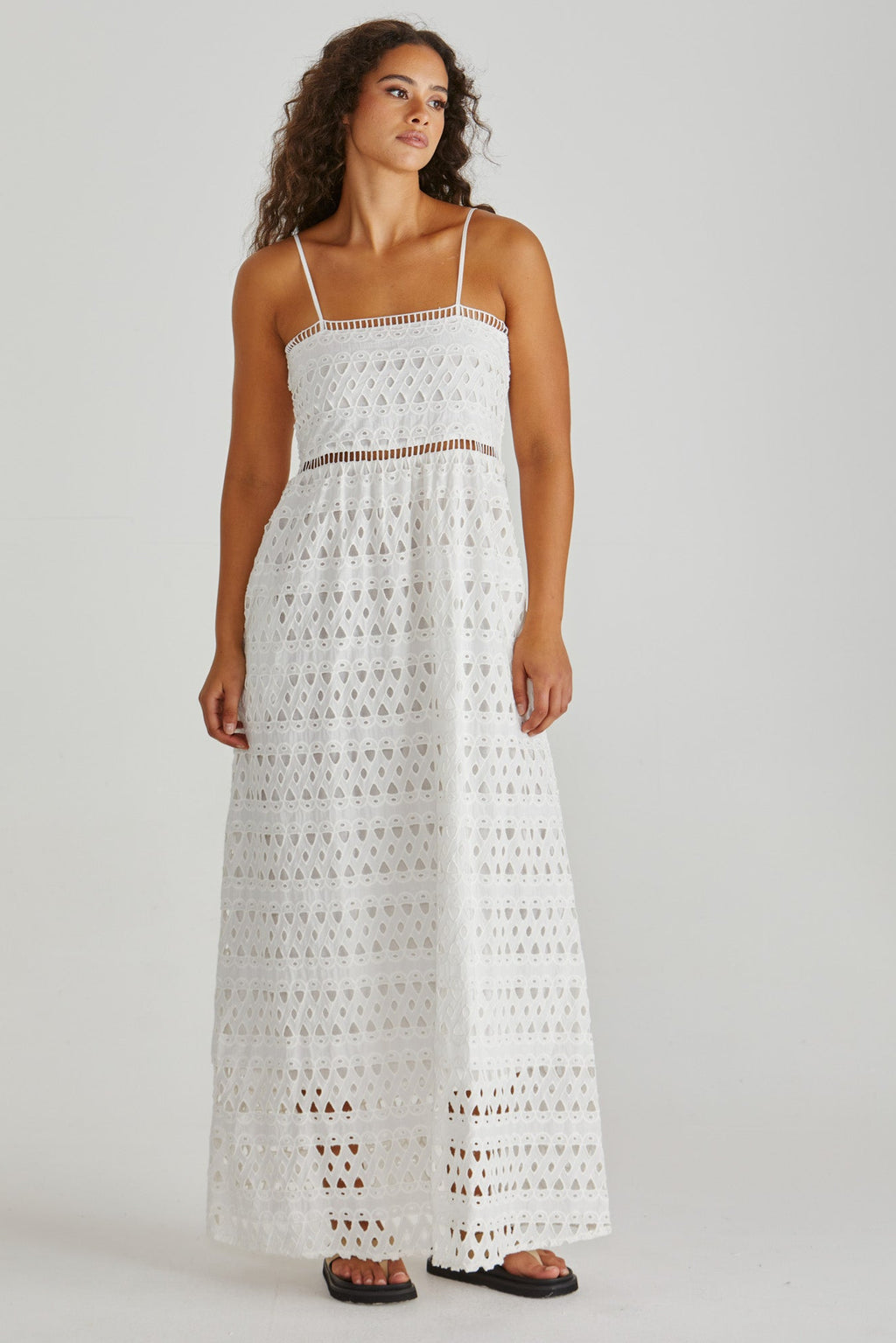 Woman wearing a white crochet dress on a plain background