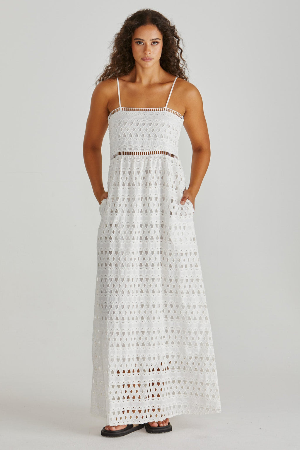 Woman wearing a white crochet dress on a gray background