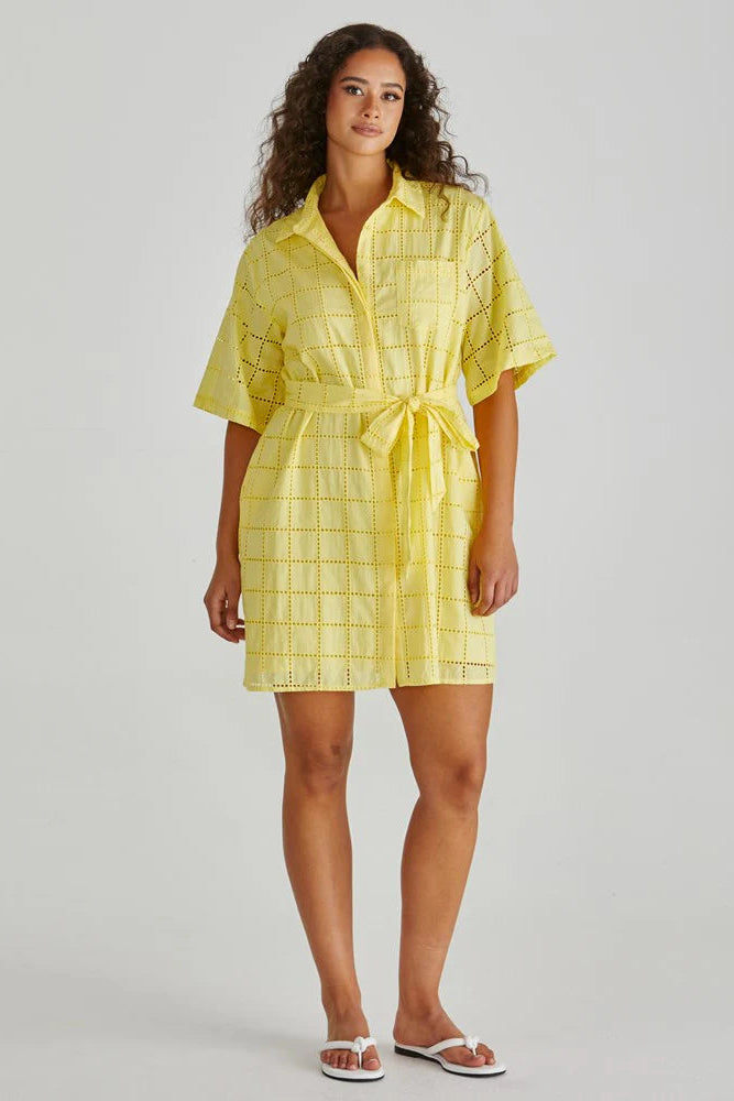 Woman wearing a yellow checkered dress on a plain background