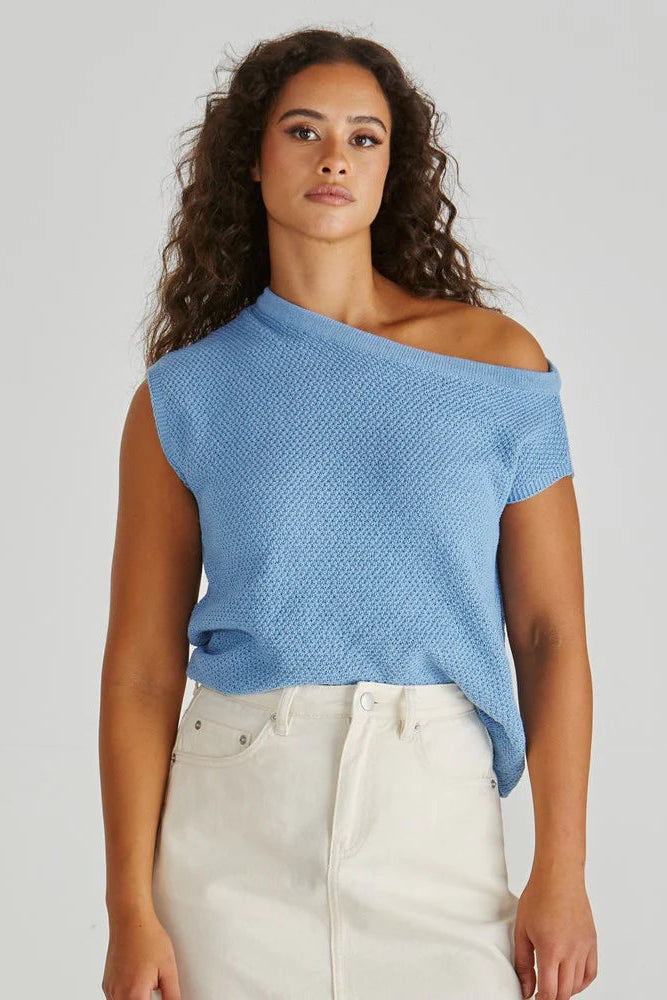 Woman wearing a blue one-shoulder top against a plain background