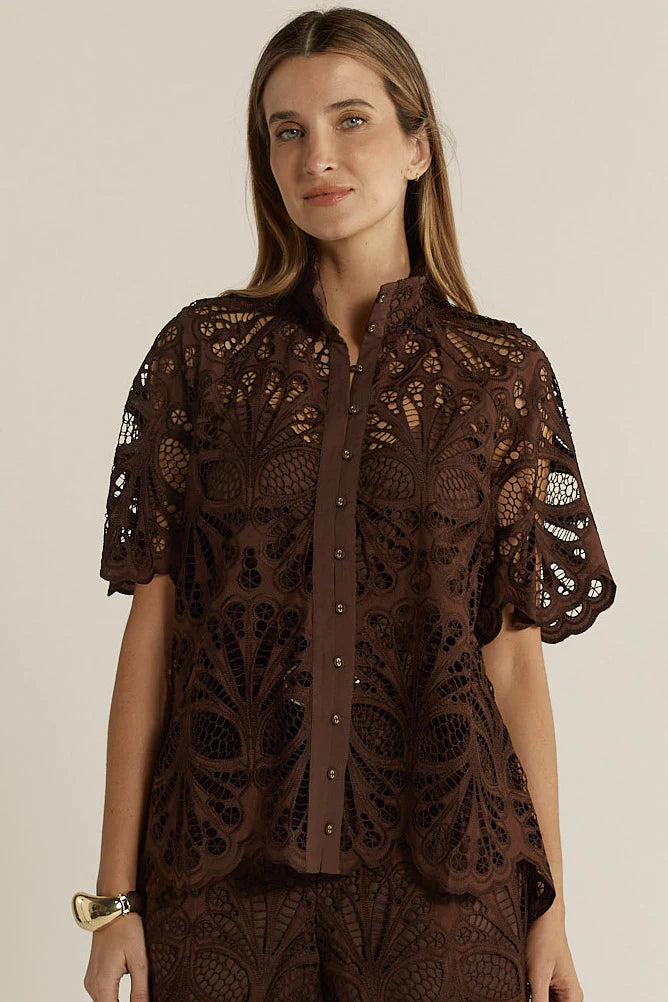 Woman wearing a brown lace top against a neutral background