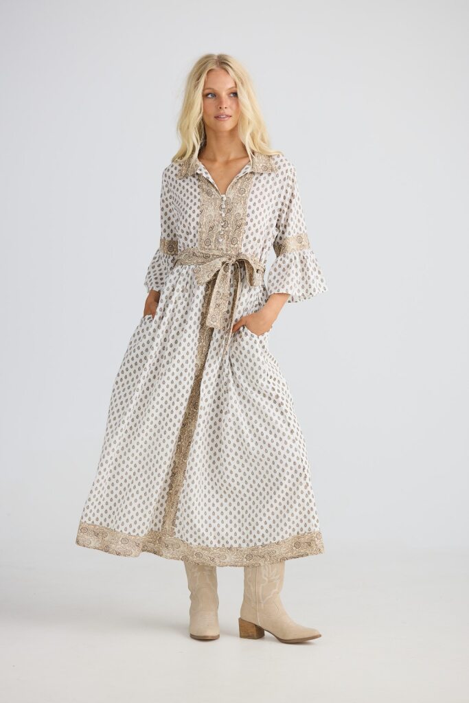 Woman wearing a patterned dress with a belt on a white background