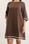 Brown dress with white trim on a plain background