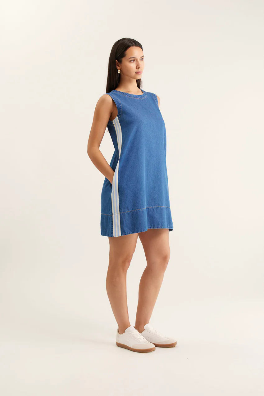 Woman wearing a blue dress with white stripes on a plain background