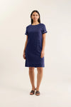 Woman wearing a navy dress with white trim on a light beige background