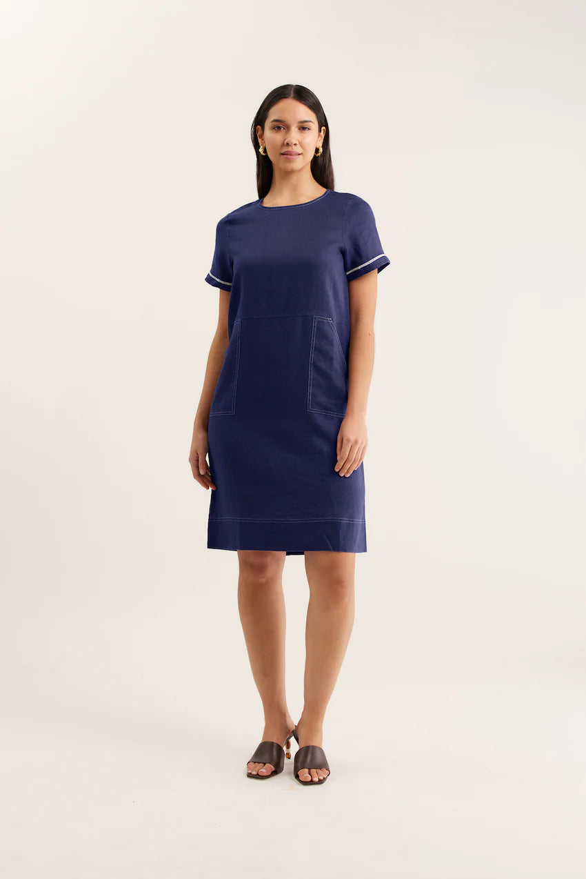 Woman wearing a navy dress with white trim on a light beige background