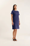 Woman wearing a navy dress with white trim on a white background