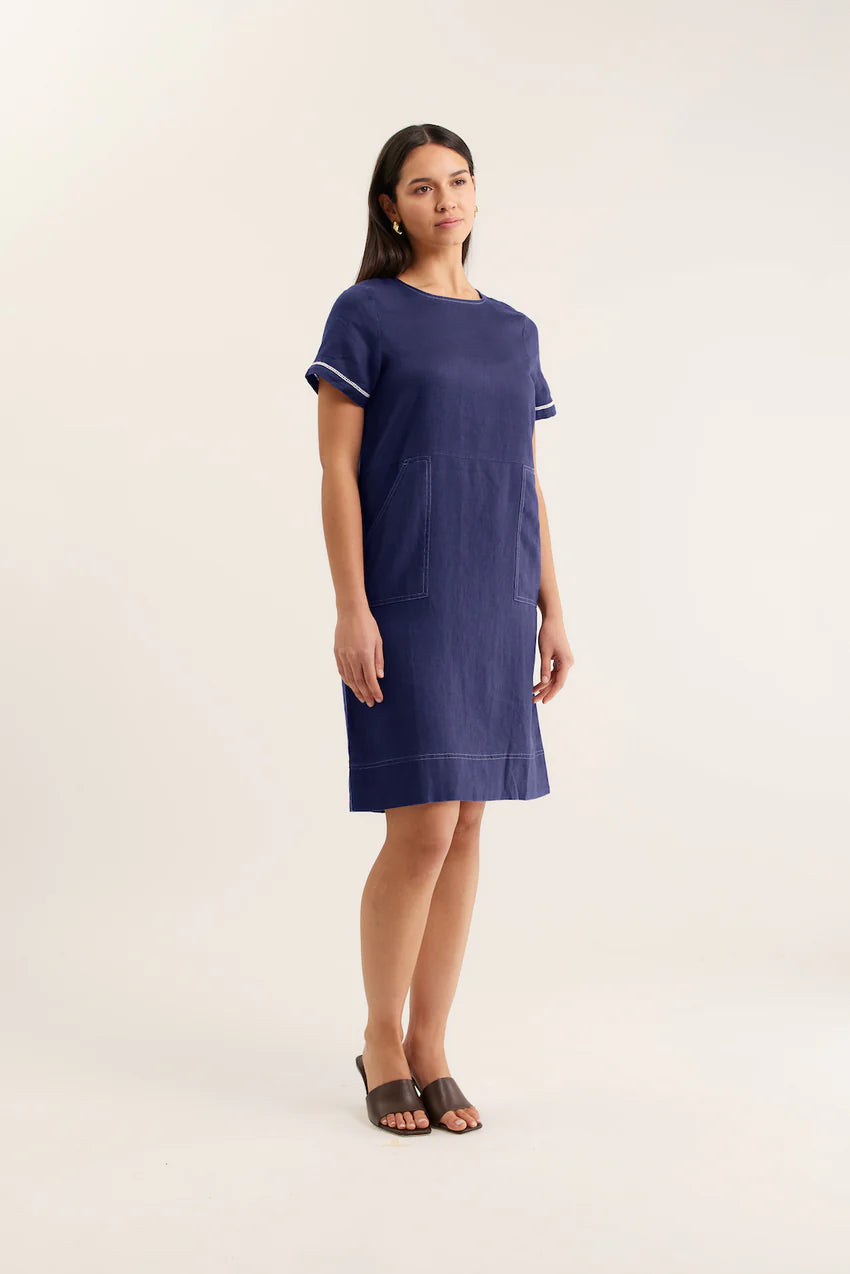 Woman wearing a navy dress with white trim on a white background