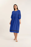 Woman wearing a blue dress with black trim on a white background