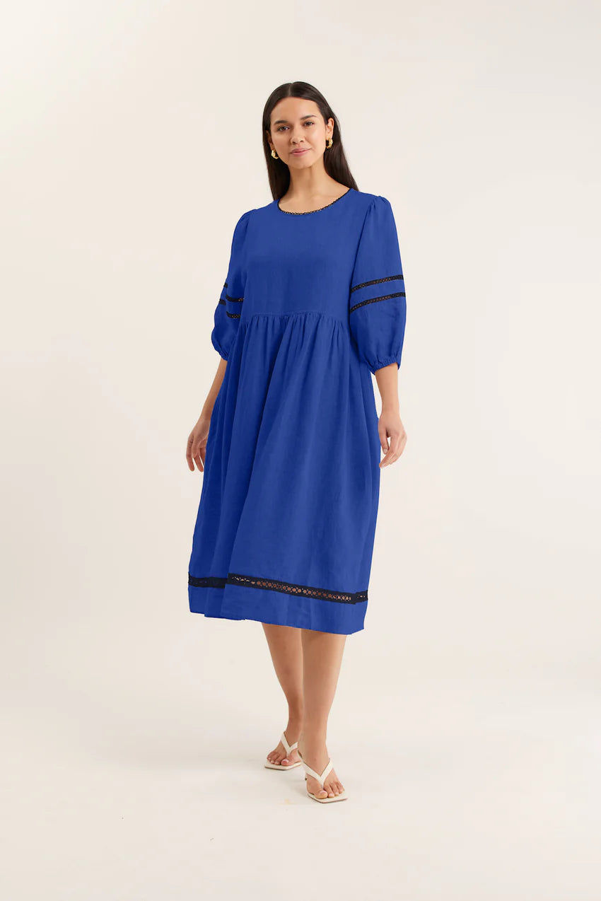 Woman wearing a blue dress with black trim on a white background