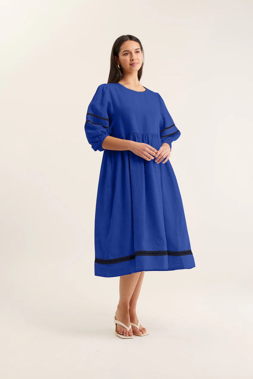 Woman wearing a blue dress with black trim on a white background