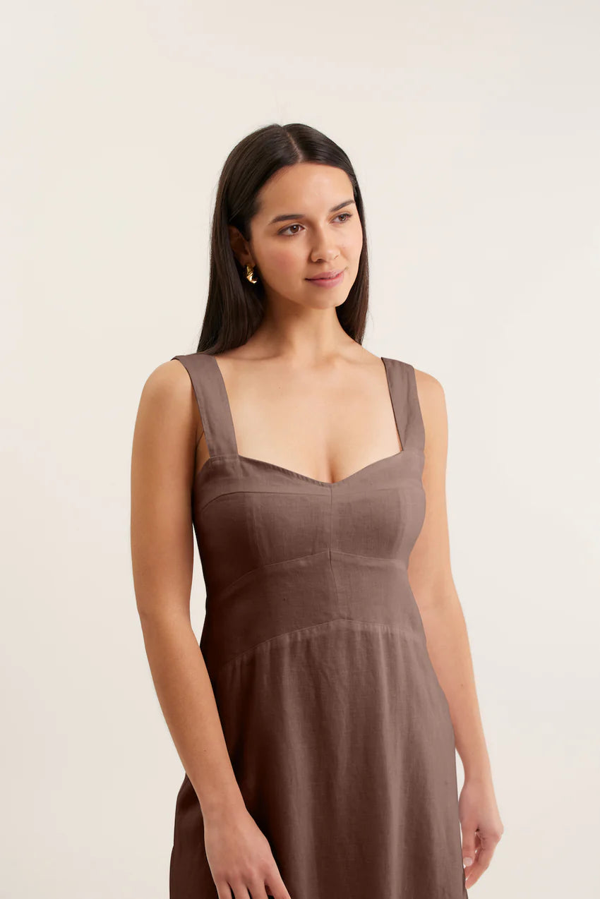 Woman wearing a brown dress against a plain background