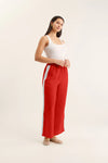 Woman wearing red pants with a white stripe on a beige background