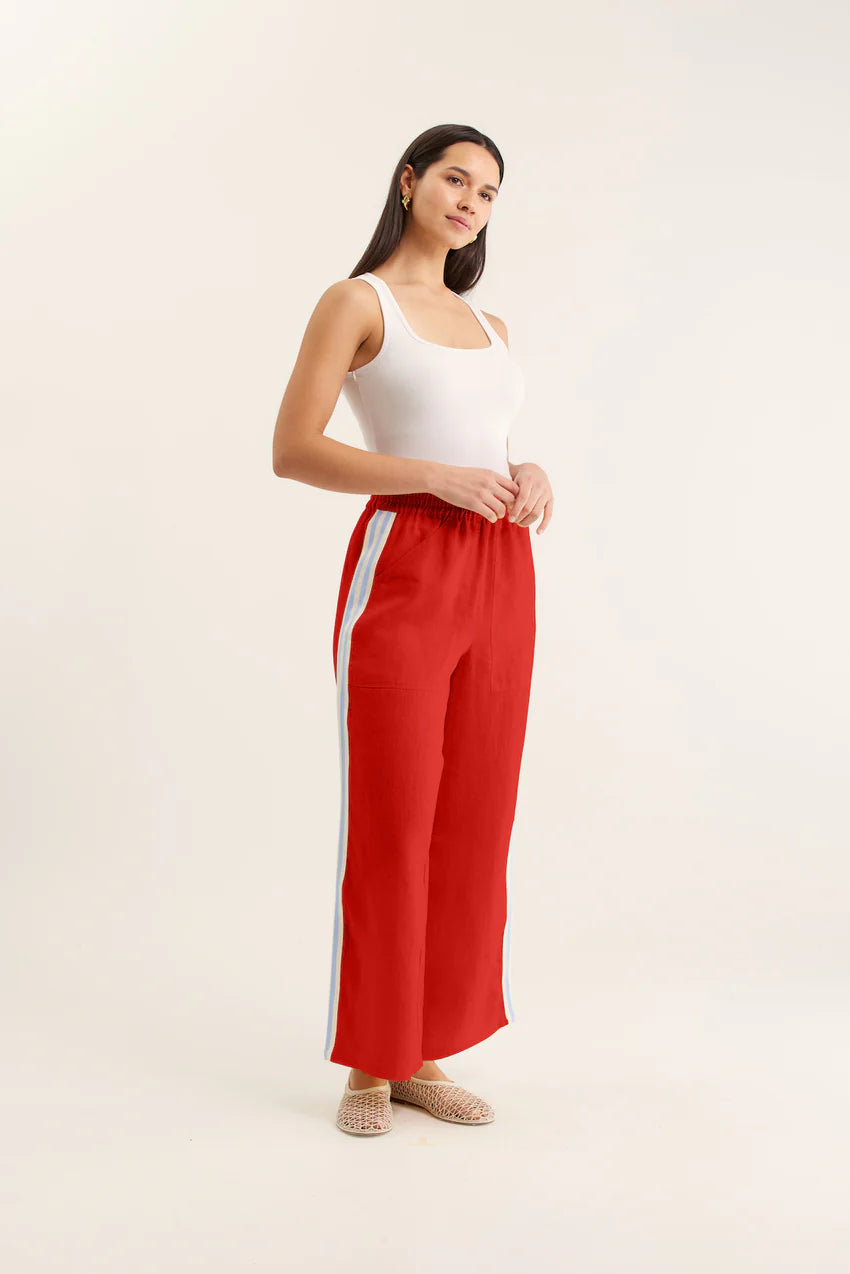 Woman wearing red pants with a white stripe on a beige background