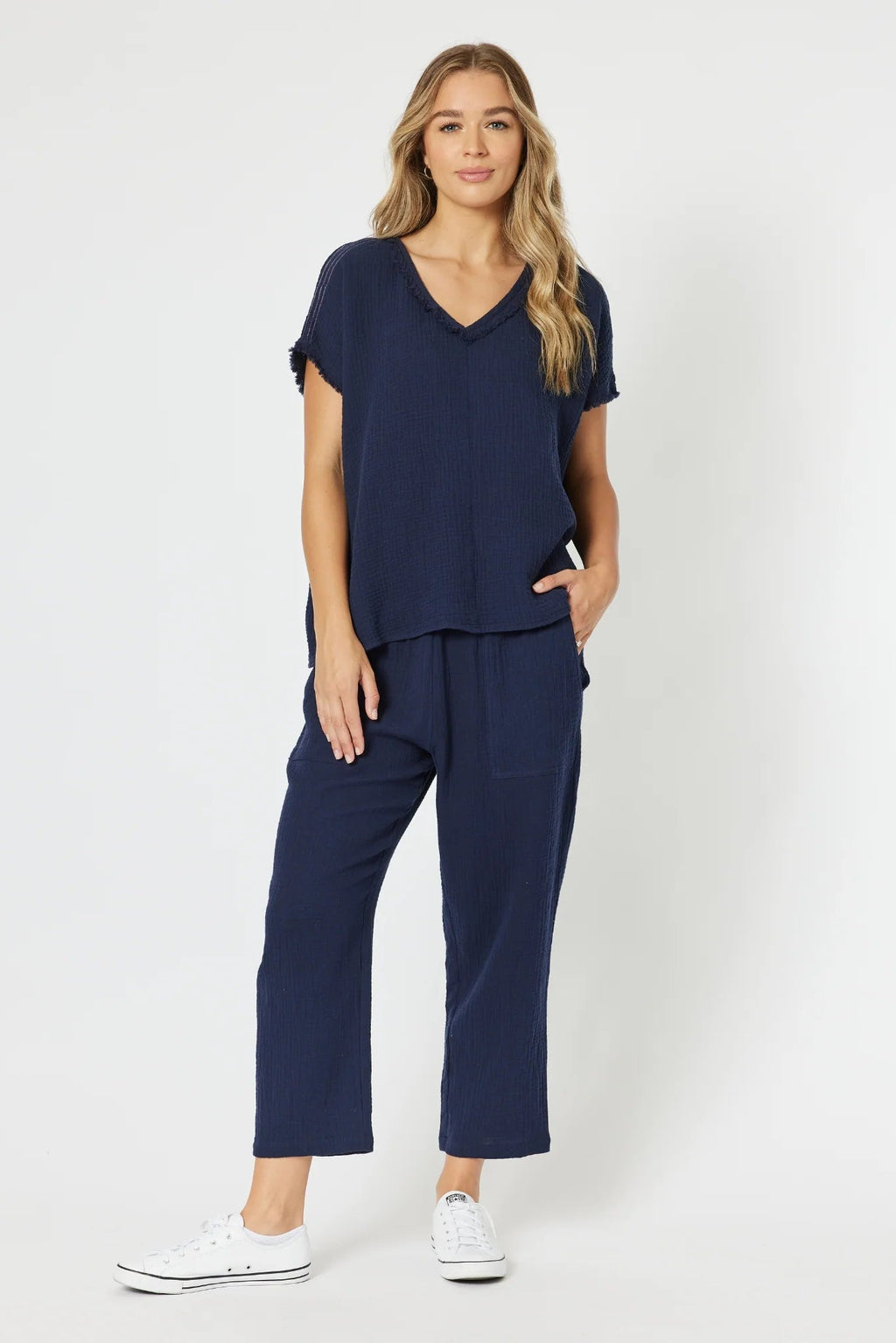 Woman wearing a navy blue outfit with white sneakers on a white background