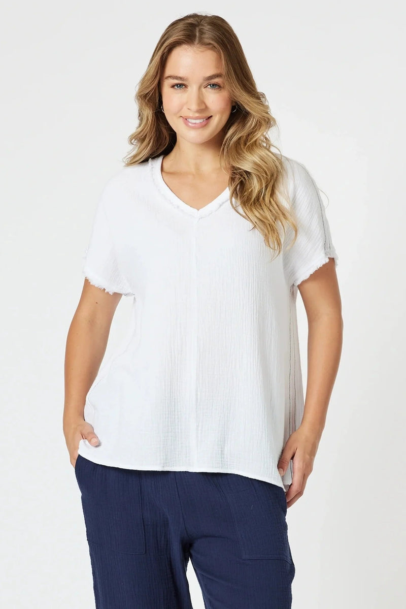 Woman wearing a white blouse and navy pants on a white background