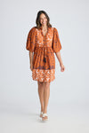 Woman wearing an orange patterned dress on a white background