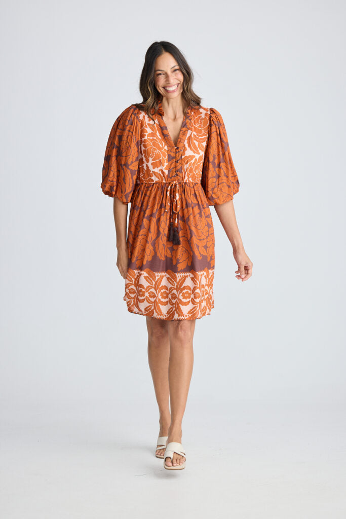 Woman wearing an orange patterned dress on a white background