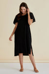 Woman wearing a black dress with lace sleeves against a beige background