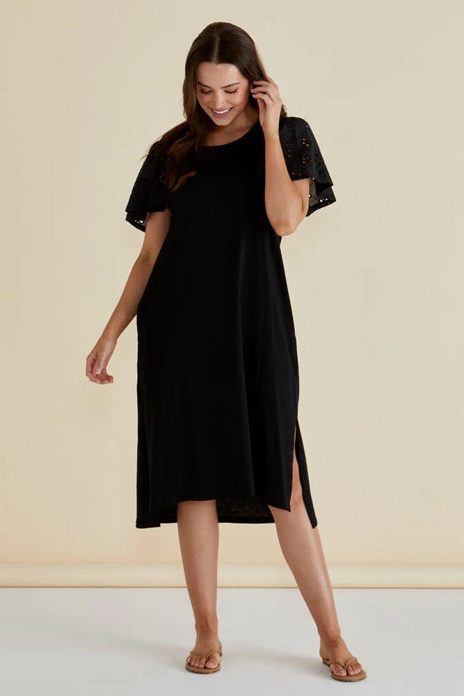 Woman wearing a black dress with lace sleeves against a beige background