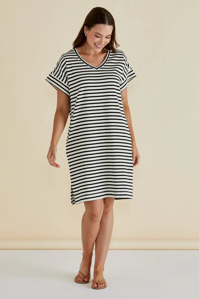 Woman wearing a black and white striped dress against a beige background