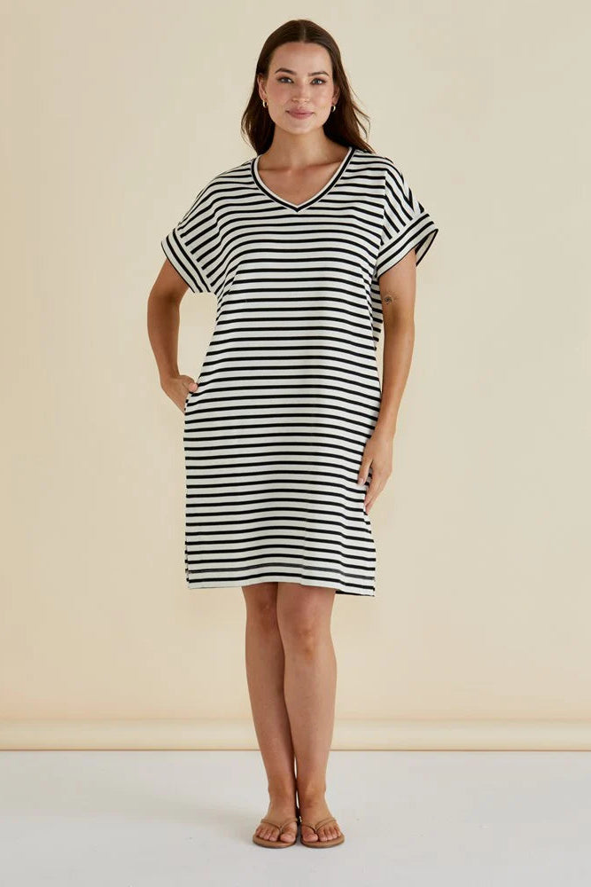 Woman wearing a black and white striped dress against a beige background