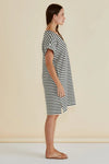 Woman wearing a black and white striped dress against a beige background