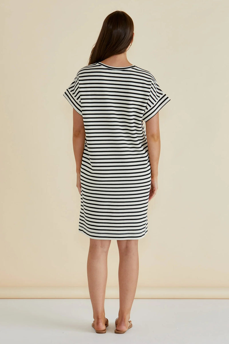 Woman wearing a black and white striped dress against a beige background
