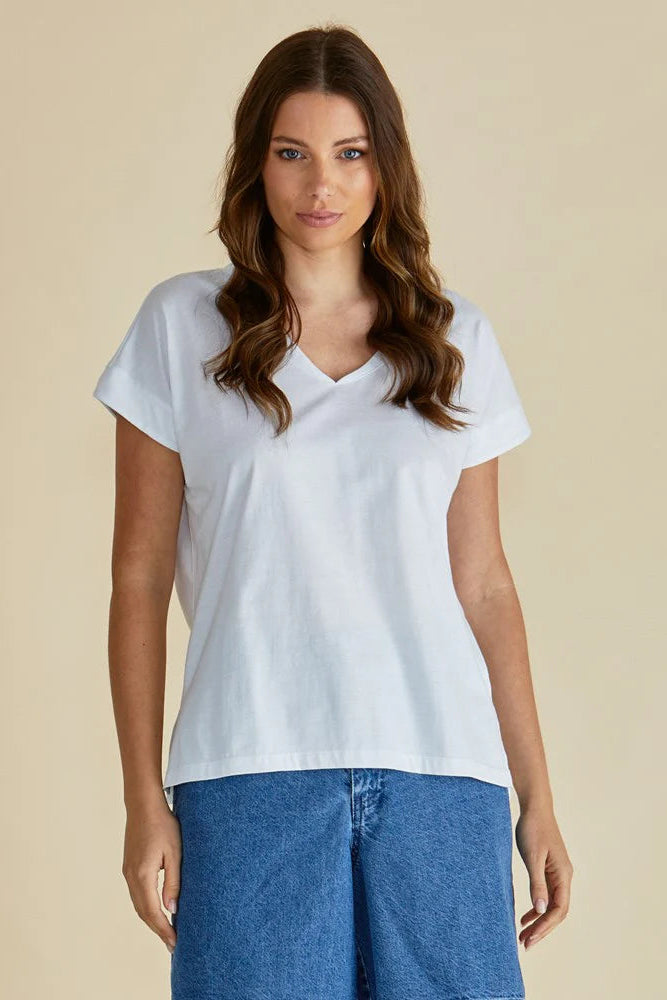 Woman wearing a white t-shirt and blue jeans against a beige background