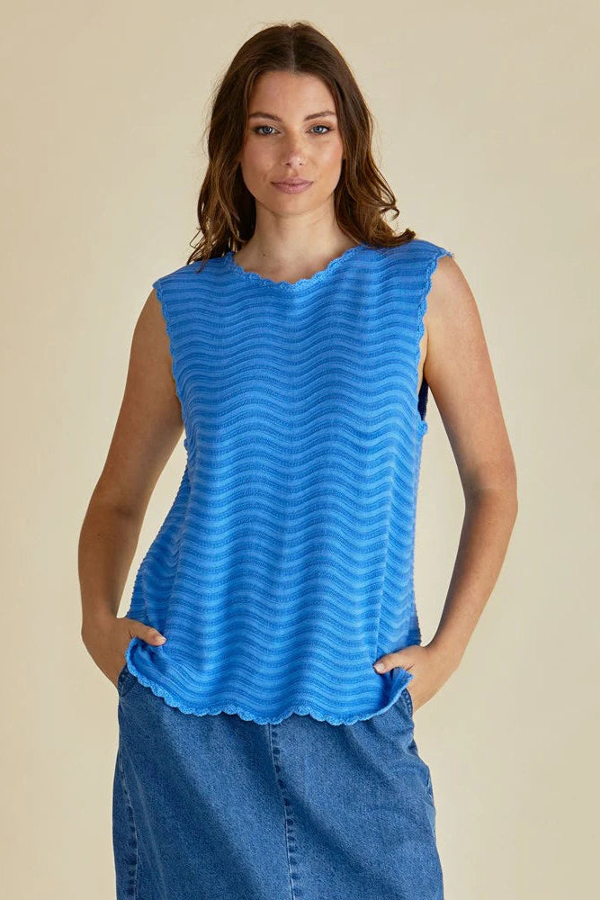 Woman wearing a blue sleeveless top with a beige background