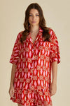 Woman wearing a red patterned dress against a beige background