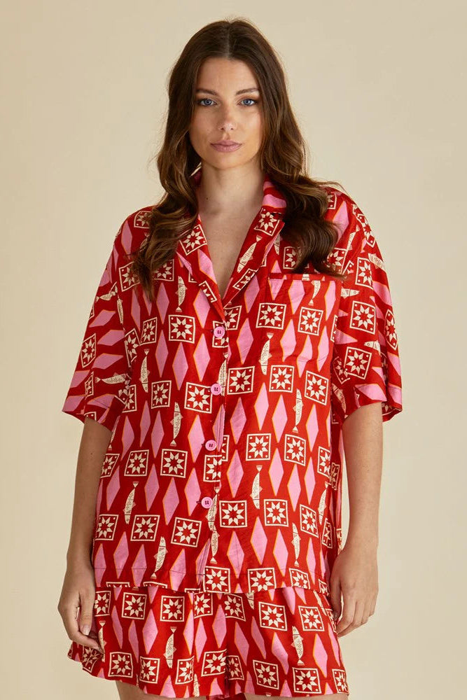 Woman wearing a red patterned dress against a beige background