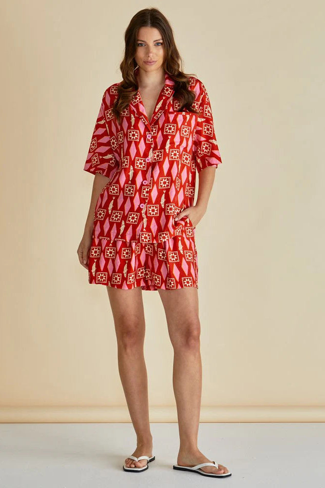 Woman wearing a red patterned dress against a beige background