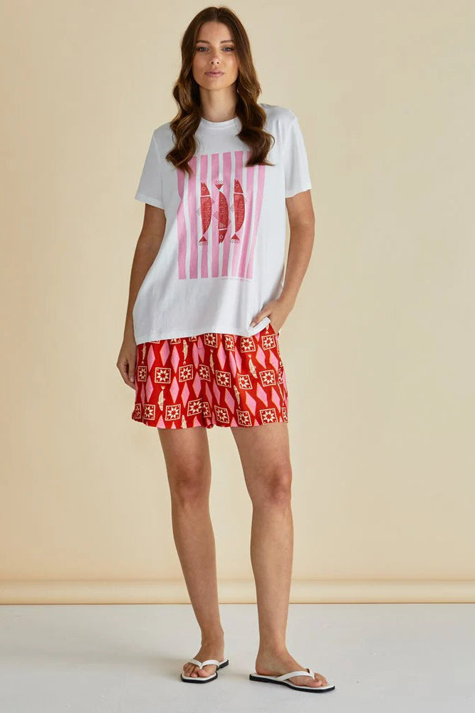 Woman wearing a white t-shirt with a graphic design and a red patterned skirt on a beige background
