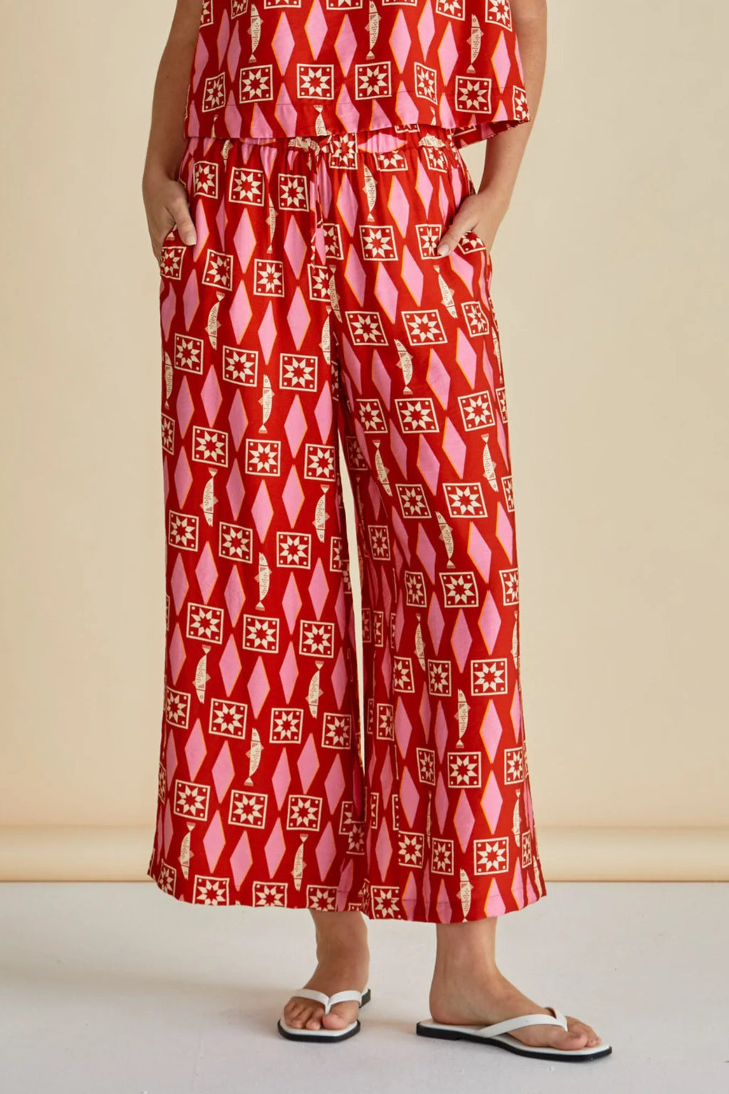 Person wearing a red patterned jumpsuit on a beige background