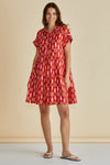 Woman wearing a red patterned dress against a beige background
