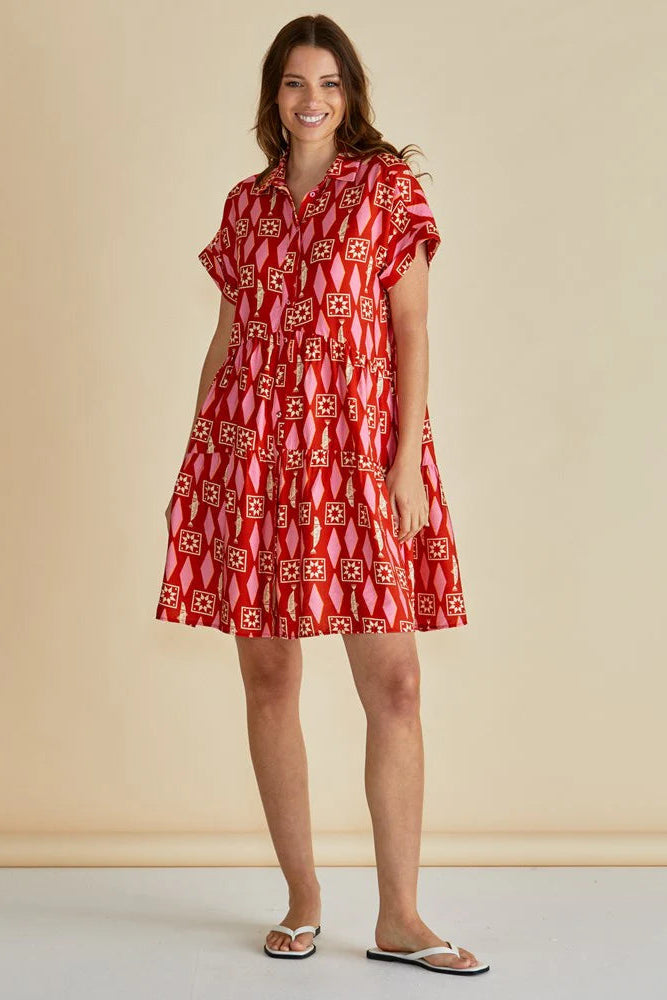 Woman wearing a red patterned dress against a beige background