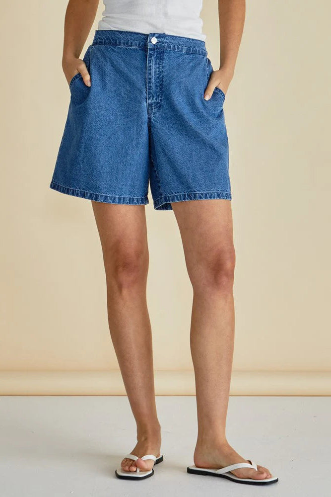 Person wearing blue denim shorts on a beige background