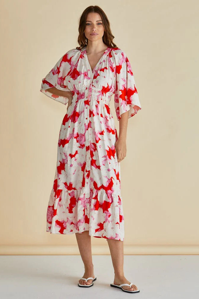 Woman wearing a red and white floral dress against a beige background
