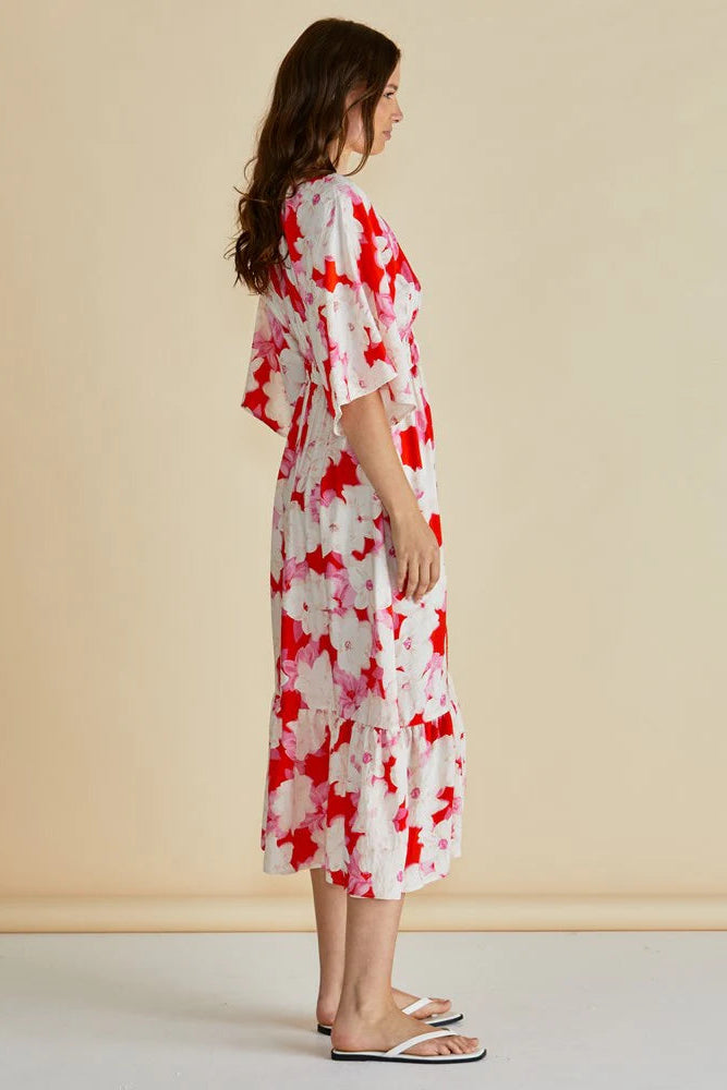 Woman wearing a red and white floral dress against a beige background