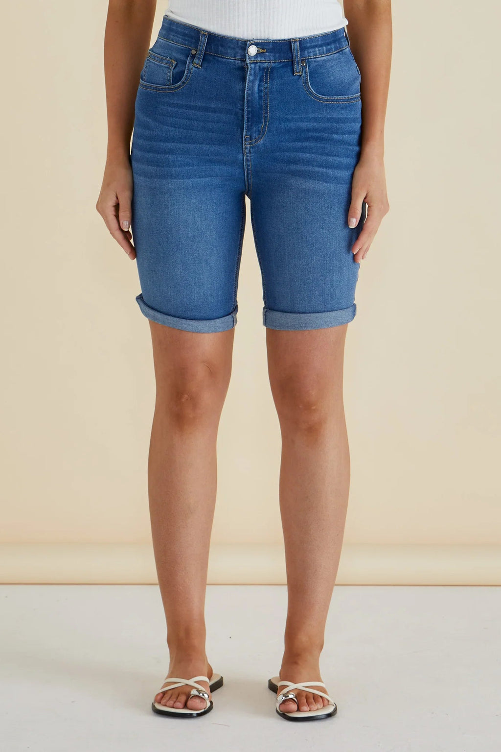 Person wearing blue denim shorts on a beige background