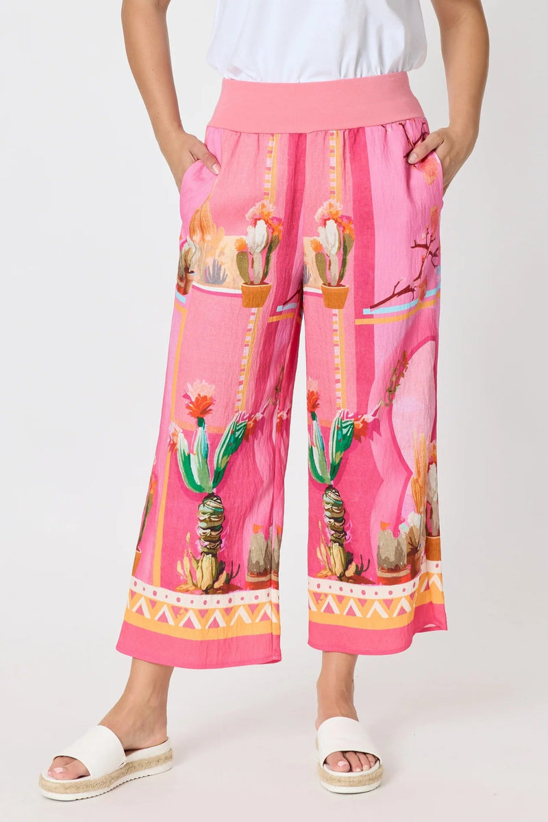 Pink pants with cactus print worn by a person on a white background