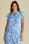 Woman wearing a blue and white leaf-patterned dress against a beige background