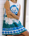 Person wearing a sleeveless dress with blue and green patterns and text.