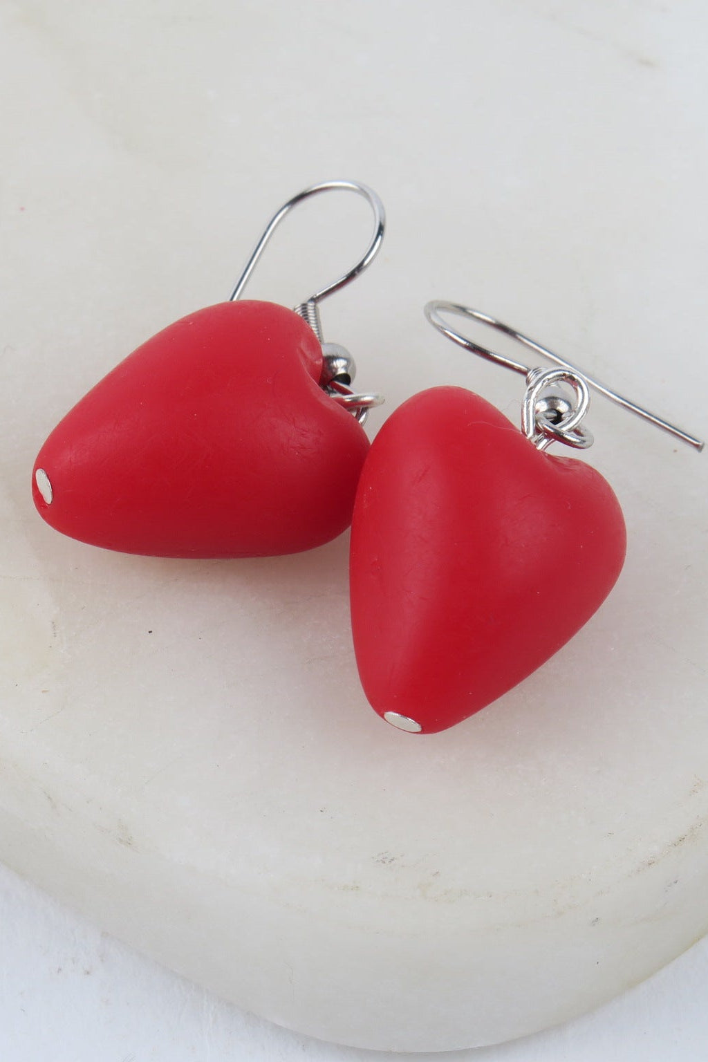 Red heart-shaped earrings on a white background