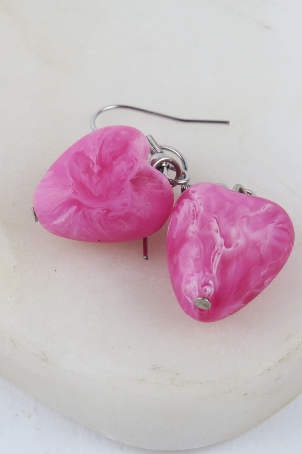 Pink heart-shaped earrings on a white background