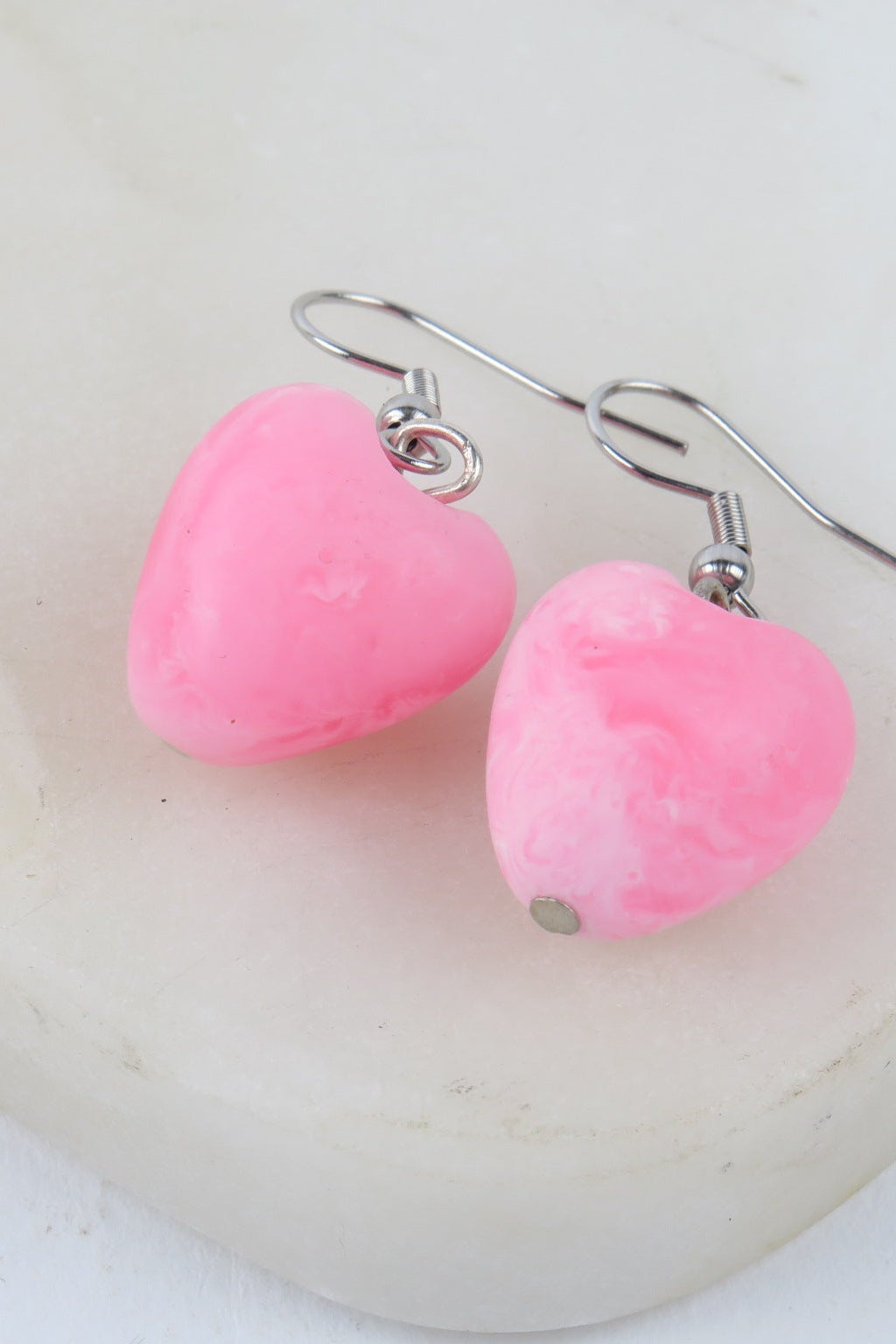 Pink heart-shaped earrings on a white background