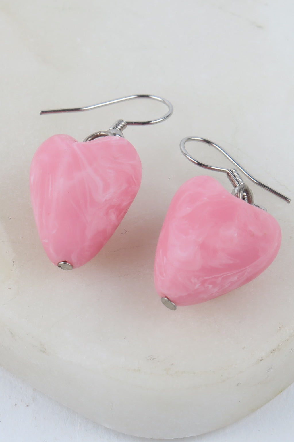 Pink heart-shaped earrings on a white background