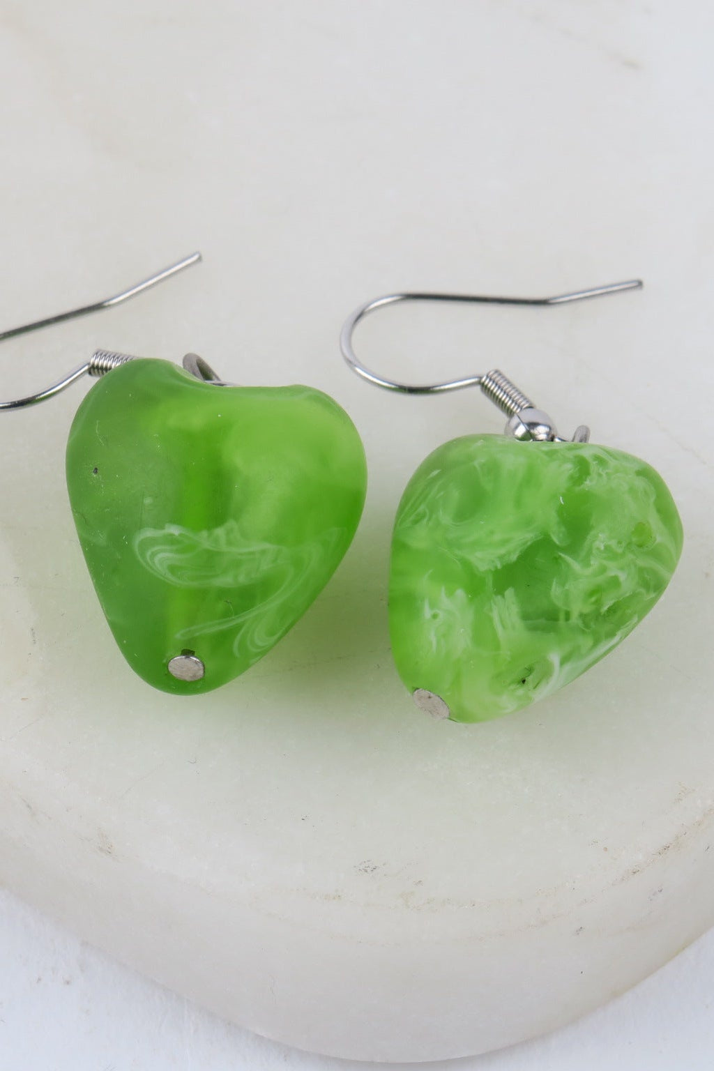 Green marbled heart-shaped earrings on a white background